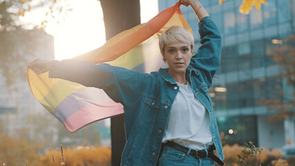 beutiful young woman with short hair waving rainbow flag in the park. High quality photo - obrazy, fototapety, plakaty