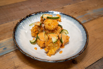 A delicious plate of fried chicken with chilli mayonnaise mayo and cucumber slices on a wooden kitchen work top