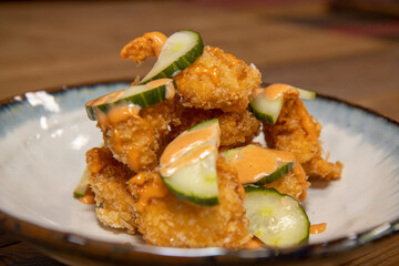 A delicious plate of fried chicken with chilli mayonnaise mayo and cucumber slices on a wooden kitchen work top