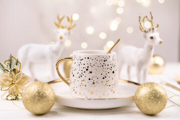 Beautiful composition with new year's deer and a white Cup with a Golden new year's drink.