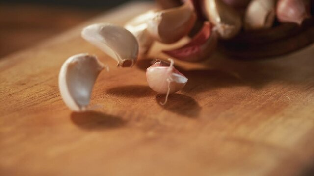 Garlic and small onions pass in front of the camera on the wooden floor. Macro, 4K, Phantom Camera, Super Close-up.