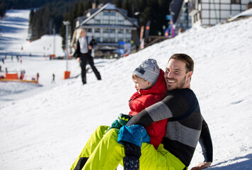 Father and son sliding on mountain slope
