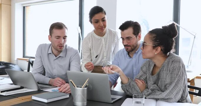 Motivated young multiracial startup developers discussing online project presentation on computer for fundraising investment. Smart skilled diverse colleagues analyzing marketing research results.