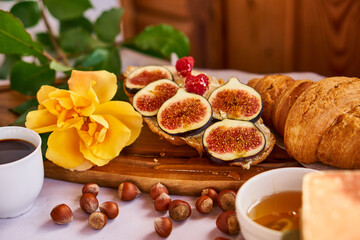 Coffee and croissant for Breakfast. French toast with figs near a yellow rose. High quality photo