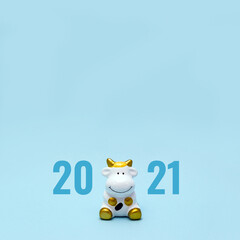 Toy cow and numbers 2021 on blue background. The white bull is a symbol of the New Year according to the Eastern calendar. Copy space