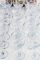 glass goblets stand in rows next to wine bottle