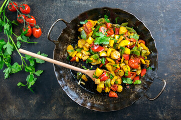 Traditional French ratatouille with vegetable and potatoes offered as top view in a rustic wrough-iron skillet with copy space
