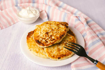 Cottage cheese pancakes with sour cream on white background, breakfast or lunch