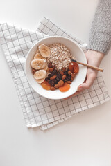 Carbohydrate healthy breakfast. Oatmeal with dried fruits on a white plate. View from above