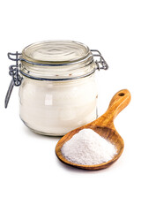 Glass jar and wooden spoon with baking soda on isolated white background, chemical compound in crystalline powders, used as antacid or as yeast