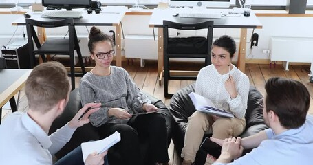 Top view group of smiling mixed race people sitting in comfortable soft chairs at meeting with psychologist in office, discussing problems. Happy diverse colleagues involved in teambuilding activity.