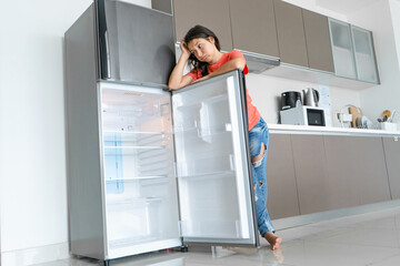 The girl is surprised at the empty refrigerator. Lack of food. Food delivery