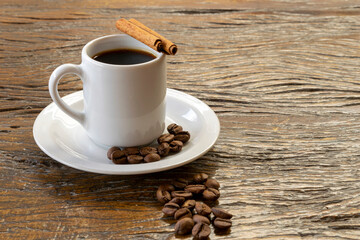 cup with coffee, cinnamon and coffee beans on rustic table