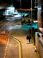 Romantic couple walking down a pathways next to a main road being lit by one street light
