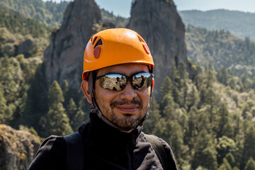 Closeup shot of a male rock climber on the top of the mountain in a sunglasses