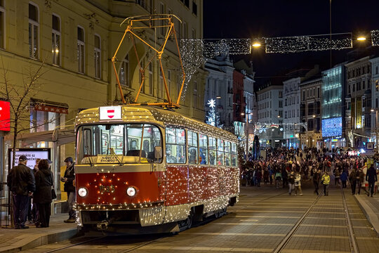 Brno, Czech Republic. Christmas tram at the stop Liberty Square, and lot of people at Christmas Market on the square in night.