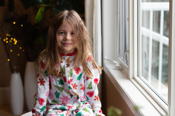 girl wearing Christmas Pj's by window