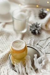 Details of still life in the home interior living room. Orange Opened plastic container, jar.of cream over Christmas lights bokeh in home. holiday decoration, magic Christmas. Selected focus