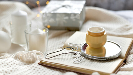 Details of still life in the home interior living room. Orange Opened plastic container, jar.of cream over Christmas lights bokeh in home. Winter mood, holiday decoration, magic Christmas. Selected fo