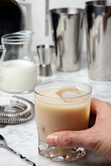 Man's hand grabbing a White Russian Cocktail with Vodka, Coffee Liquor and Cream