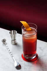 Americano Cocktail with Orange Twist on a marble table. Red sofa as a background
