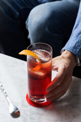 Man's hand grabbing Americano Cocktail with Orange Twist