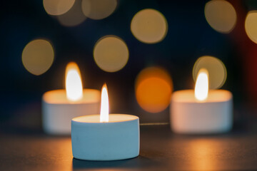 Fototapeta na wymiar Three burning candles in front of a beautiful colorful circle shiny bokeh background