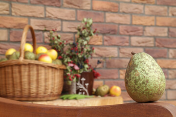 Detail on the fresh collected pear with romantic background behind it. There is wicker basket filled with just collected pears and apples from garden. Decorated with autumn wild berries. Old England v