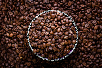 Bowl of coffee beans on the bokeh background filled with coffee beans. roasted coffee beans