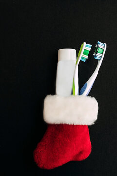 Christmas kit from the dentist. Red sock with two toothbrushes and a tube of toothpaste on a black background.