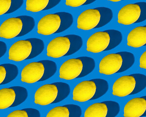 A pattern of bright yellow lemons with a pronounced shadow on a bright blue background. Lemon set, healthy food.