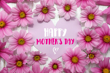 Happy Mothers Day. Background with frame of pink flowers, heart shaped card, text, white wood.