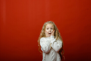 Little cute girl in the studio on a red background with Christmas toys