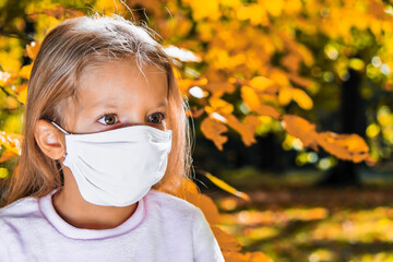 Girl in an antivirus mask in the autumn park.