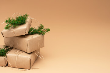 Eco Christmas retro gifts. Handmade Christmas boxes wrapped in craft paper and fir branches on beige gradient background. Zero waste New Year backdrop with Copy space. 