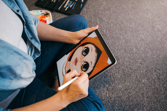 Creative hobby and freelance artistic work job. Caucasian woman artist illustrator painting drawing on a touch pad digital tablet with stylus. Process of creating illustration. Unique profession.