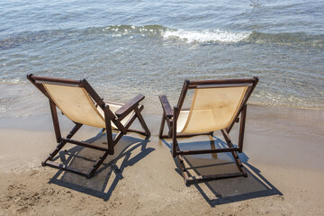 Two sun loungers stand on the sandy beach against the sea