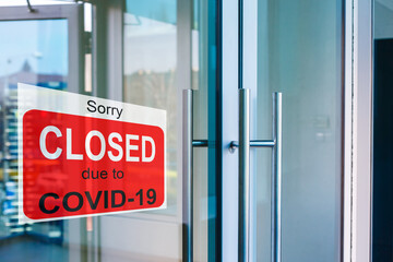 Business center closed due to COVID-19, sign with sorry in door window. Stores, restaurants,...