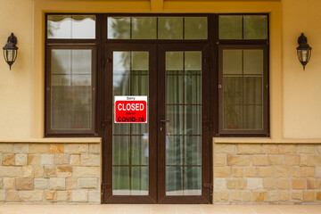 Fototapeta premium Business center closed due to COVID-19, sign with sorry in door window. Stores, restaurants, offices, other public places temporarily closed during coronavirus pandemic. Economy hit by corona virus