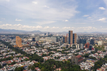 Aérea sobre la zona residencial de Polanco con una vista espectacular al skyline de la zona de oficinas y rascacielos y un cielo azul nublado.