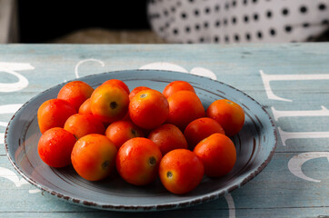 Plate full of fresh cherry tomatoes on a contrasting blue background