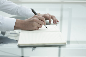 Office worker's hand writes in notebook