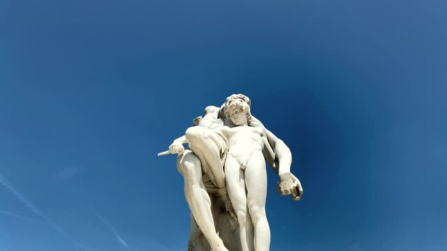 Footage of historical statue at famous public garden called "Jardin Des Tuileries" in the 1st arrondissement of Paris. It is a sunny summer day. Camera pans right.
