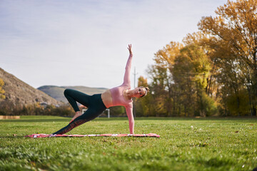 Woman practicing yoga in the park - relaxing in nature