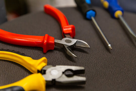 Laying a wire pair of pliers and screwdrivers locksmith work tool close-up on a dark background