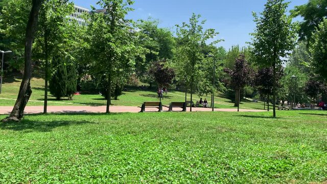 Footage of people walking and relaxing at city park called "Macka Demokrasi Parki" in Nisantasi area of Istanbul. Beautiful nature scene. Urban youth culture concept. It is a sunny summer day.
