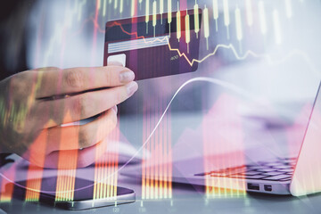 Multi exposure of woman on-line shopping holding a credit card and financial graph drawing. Stock market E-commerce concept.