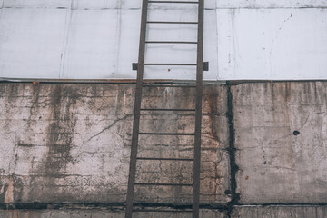 Rusty fire escape stairs on concrete wall of an abandoned industrial building