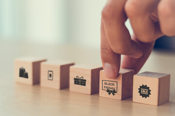 man hand arranging on wooden cube block with retail with black Friday day icon