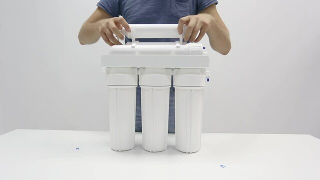 Male hands dismantling small parts from reverse osmosis water filter